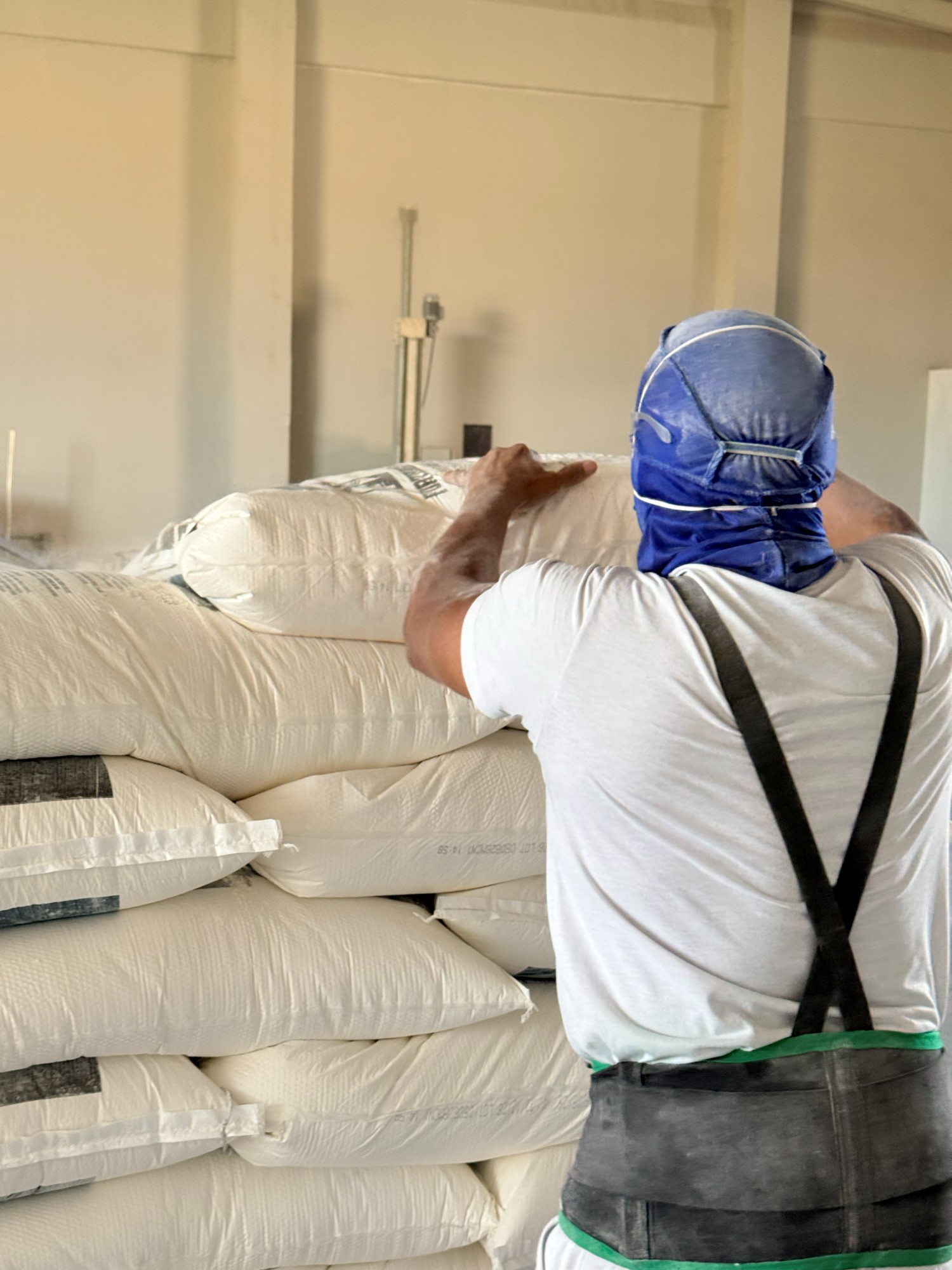 Operário carregando saca de farinha na produção
